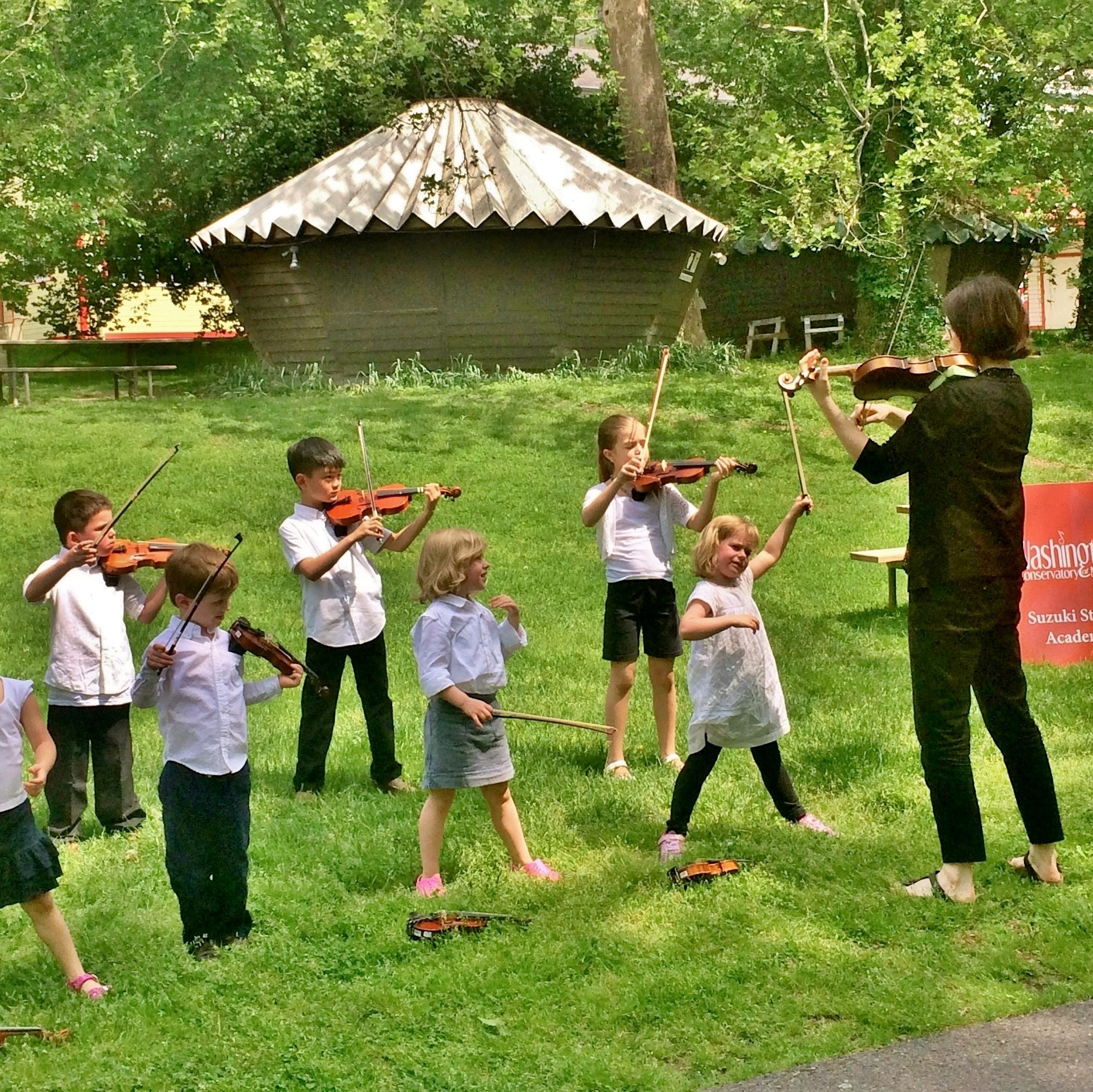 Students taking a violin lesson outside at Glen Echo Park