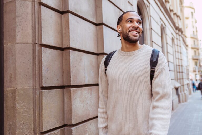 Smiling student walking in urban city street listening to music