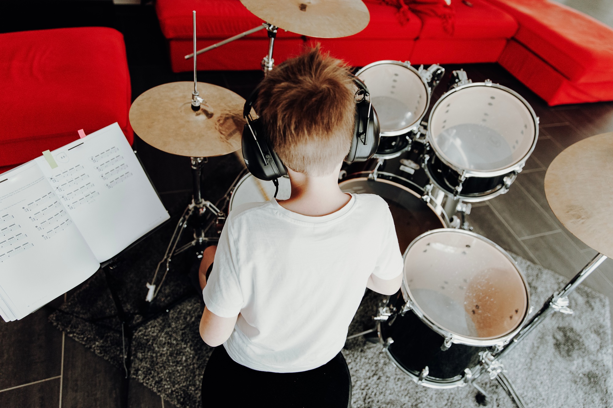 Young boy learning playing drums at home. Children playing instruments.