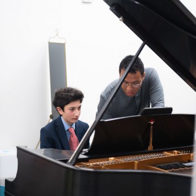 Music instructor teaching a student to play piano
